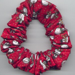 May include: Red fabric hair scrunchie with a white snowman pattern.