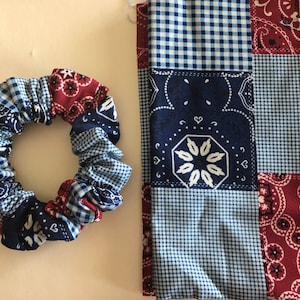 May include: A blue and red patchwork fabric scrunchie and a matching fabric square. The fabric has a gingham pattern and a paisley pattern.