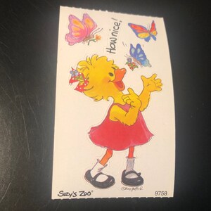 May include: A yellow chick wearing a red dress and a red and white headband with blue flowers. The chick is smiling and has its arms raised. The chick is surrounded by butterflies. The text "How nice!" is written above the chick. The text "Suzy's Zoo" is written in the bottom left corner of the image. The number "9758" is written in the bottom right corner of the image.