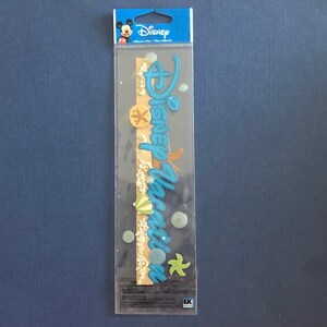 May include: A sheet of Disney Vacation stickers with a blue and white color scheme. The stickers feature a sand dollar, starfish, and a seashell. The stickers are on a clear plastic sheet with a blue border.