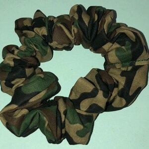 May include: A green, brown, and black camouflage patterned scrunchie.