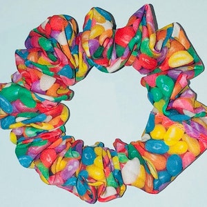 May include: A colorful hair scrunchie with a jelly bean print. The scrunchie is made of fabric and has a gathered design.