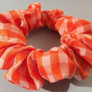 May include: Orange and white gingham scrunchie hair tie.