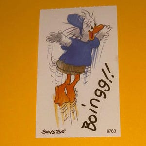 May include: A cartoon image of a duck in a blue shirt and hat, brown shorts, and orange feet, jumping with the word "Boingg!!" written in black. The image is on a white rectangle with the text "Suzy's Zoo" and the number "9763".
