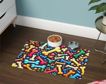 May include: A colorful pet feeding mat with a repeating pattern of cartoon dog bones in various colors. The mat is on a dark wood floor, with a white ceramic bowl filled with pet food and a stainless steel bowl.