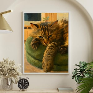 Peut inclure: Une impression encadrée d'un chat tigré se reposant sur un coussin vert. Le chat a des poils bruns et noirs et des yeux bleus. L'œuvre est exposée sur une étagère en bois avec une horloge, un vase et des plantes.