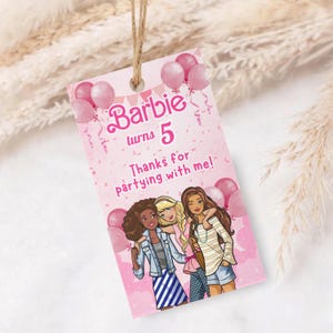 May include: Pink gift tag with the text "Barbie turns 5" and "Thanks for partying with me!" featuring illustrations of three girls, pink balloons, and decorative elements. The tag is strung with twine.