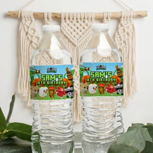 以下が含まれることがあります： 白いキャップが付いた透明なプラスチック製のウォーターボトルが2本。各ボトルには「SAM'S 8TH BIRTHAY」の文字とMinecraftをテーマにしたグラフィックが描かれたラベルが付いています。ボトルはマクラメの壁掛けの前にあります。