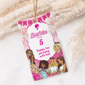 May include: A pink Barbie-themed gift tag with the text "Barbie turns 5" and "Thanks for partying with me!" The tag features illustrations of Barbie characters and pink balloons. A twine string is attached at the top.