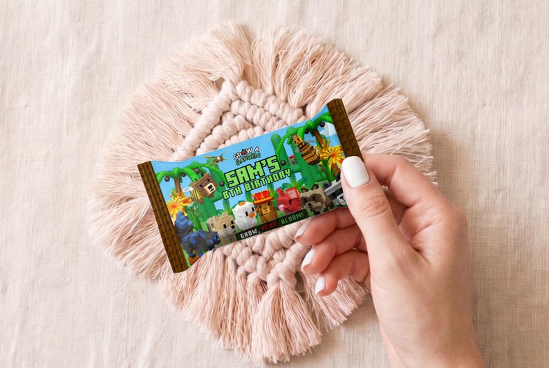 以下が含まれることがあります： Minecraftをテーマにしたカラフルなキャンディーバーの包装紙が、手によって持たれています。「SAM'S 8TH BIRTHDAY」の文字と、様々なピクセル化されたキャラクターが描かれています。デザインは緑、茶色、青で、ジャングルをテーマにしています。