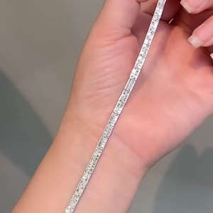 Pu&ograve; includere: Un bracciale tennis color argento caratterizzato da una fila continua di pietre trasparenti rettangolari a taglio baguette incastonate in una montatura metallica. Il bracciale presenta una chiusura a cassetta sicura e maglie flessibili.