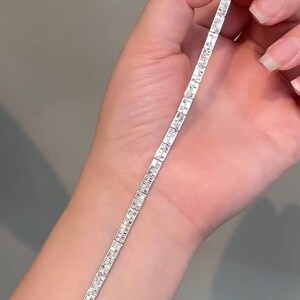 Pu&ograve; includere: Un bracciale tennis color argento caratterizzato da una fila continua di pietre trasparenti rettangolari taglio baguette incastonate in una montatura metallica. Il bracciale include una chiusura a cassetta sicura su un'estremit&agrave;.