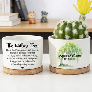 Puede incluir: Dos macetas de cerámica blanca con platillos de madera. Una tiene el texto "The Willow Tree" y un poema. La otra tiene una ilustración de sauce y el texto "Klein & Linda JUNE 2025". Un cactus con una flor amarilla está en una.