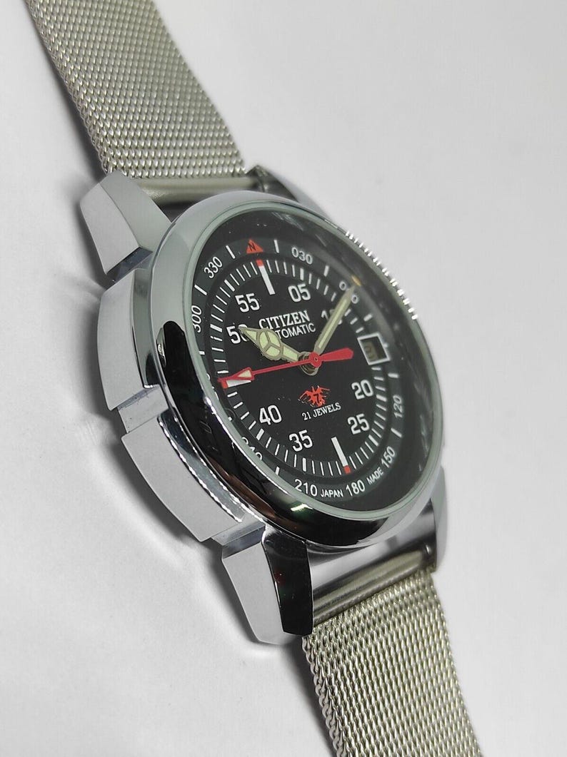 May include: A silver-toned Citizen automatic wristwatch with a black dial. The watch features red and white hands, a mesh band, and the text "CITIZEN AUTOMATIC" and "21 JEWELS".