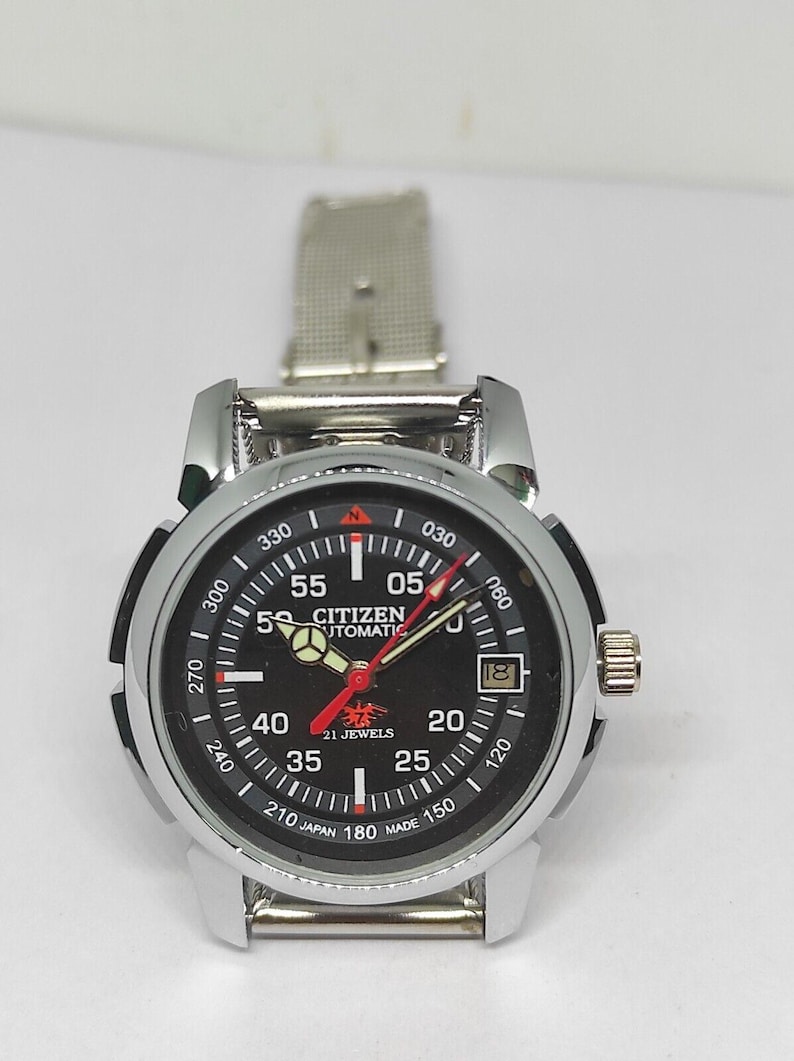 May include: A Citizen automatic wristwatch with a black dial, silver-tone case, and a silver mesh band. The watch face displays white numerals, red and white hands, and the text "Citizen Automatic 21 Jewels". The watch has a date window.