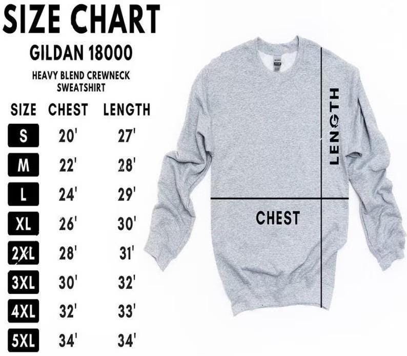 Puede incluir: Una sudadera gris claro Gildan 18000 de mezcla pesada con cuello redondo. La imagen incluye una tabla de tallas con medidas de pecho y largo en cm para las tallas S a 5XL. Las palabras "CHEST" y "LENGTH" est&aacute;n etiquetadas en la sudadera.
