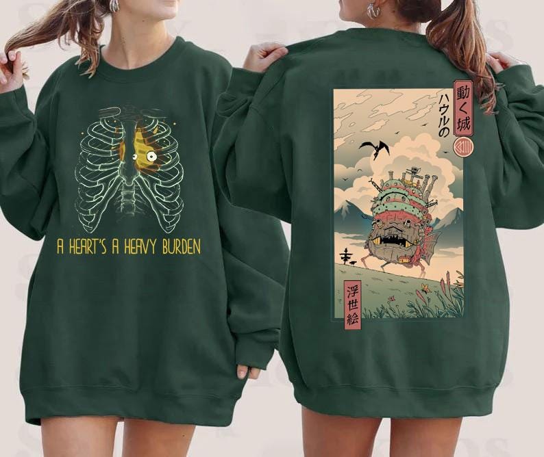 Puede incluir: Sudadera verde oscuro con un gr&aacute;fico de una caja tor&aacute;cica y un coraz&oacute;n amarillo, con el texto "A HEART'S A HEAVY BURDEN". La parte trasera presenta una ilustraci&oacute;n de estilo japon&eacute;s de un castillo en movimiento.