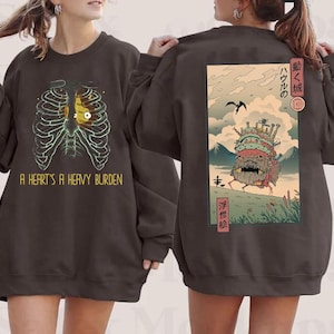 Puede incluir: Sudadera marr&oacute;n oscuro con un gr&aacute;fico de una caja tor&aacute;cica y un coraz&oacute;n, con el texto "A Heart's A Heavy Burden" en la parte delantera. La parte trasera presenta una ilustraci&oacute;n de estilo anime japon&eacute;s.