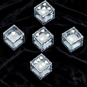 May include: Five transparent cube-shaped boxes featuring white heart-shaped patterns on the edges and sides. Each box contains a shimmering, light-reflecting silver material inside, visible through the clear walls of the containers.