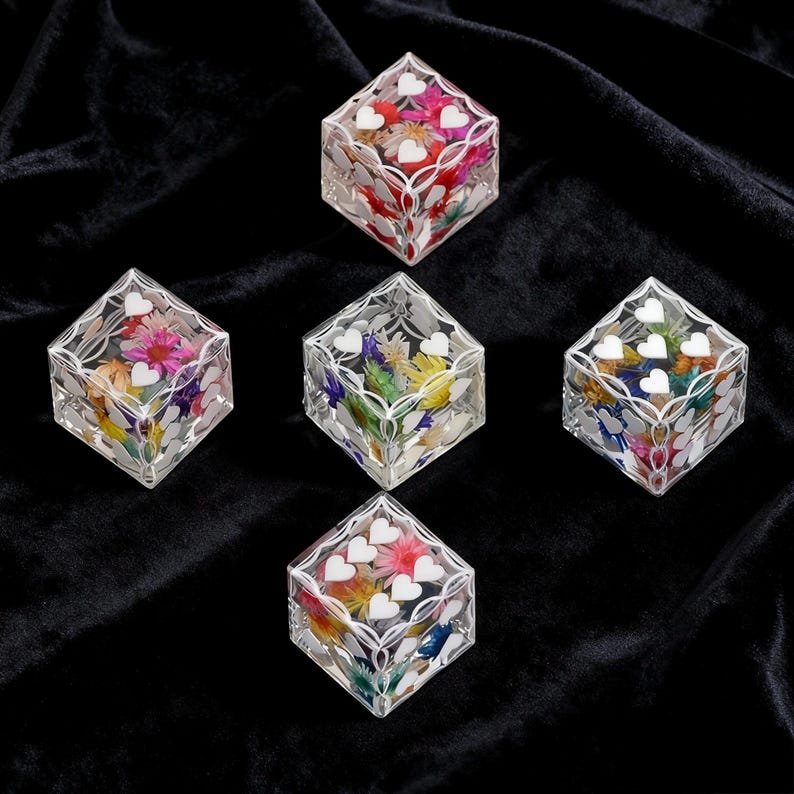 May include: Five clear resin cubes arranged in a pentagon formation. Each cube contains colorful dried flowers embedded inside and features white heart-shaped decals applied to the exterior surfaces, creating a decorative floral display.