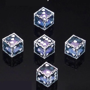 Könnte beinhalten: Ein Set aus fünf durchscheinenden blauen Würfeln mit glitzernden violetten Innenseiten. Jeder Würfel hat weiße herzförmige Augen auf den Flächen und ein weißes filigranes Randmuster entlang der Kanten dieser dekorativen Spielwürfel.