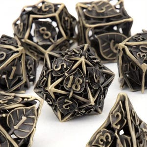 May include: A collection of bronze-colored metal polyhedral dice. Each die features a leaf design and is numbered with a contrasting font. The dice are designed for tabletop role-playing games.