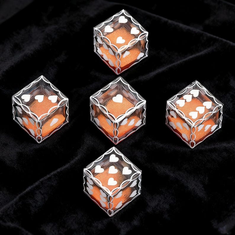 May include: Five clear plastic cube-shaped boxes, each containing a bright orange square insert. The exterior of each box features a white printed pattern of interconnected loops and small heart shapes on the top and side faces.