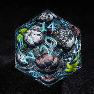 May include: A clear, multi-faceted d20 die with blue numerals and internal designs. The die features a variety of colors and textures within its transparent structure, including silver, green, and brown elements. The numbers are in a light blue color.