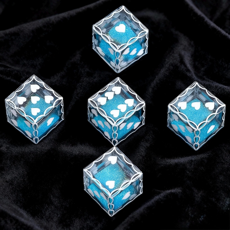 May include: Five clear, cube-shaped containers with white heart-shaped patterns printed on the edges and corners. Each container is filled with bright blue, glittery material, creating a vibrant contrast against the white heart designs.
