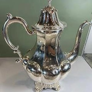 Tetera/cafetera antigua con pie, plateada.