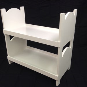 May include: White wooden bunk bed with a simple design. The bed has two levels and is made of unfinished wood.