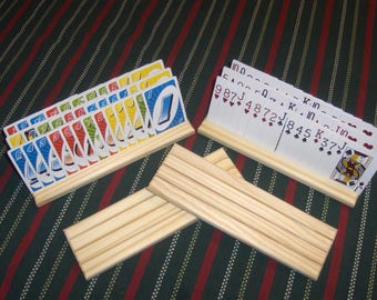 May include: Two wooden card holders with slots for holding decks of cards. One holder has a deck of standard playing cards, the other has a deck of UNO cards.