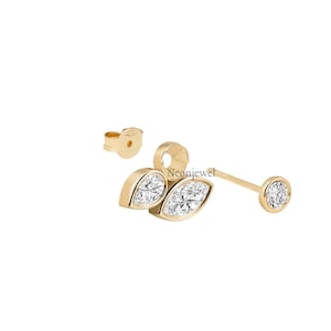 Peut inclure: Boucles d'oreilles à clous dorées avec trois pierres précieuses transparentes. Une boucle d'oreille a une pierre ronde, l'autre en a deux en forme de feuille. Les fermoirs sont également dorés.