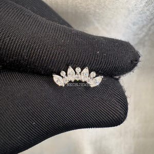 Könnte beinhalten: Ein kleines, silberfarbenes Schmuckstück in Kronenform mit mehreren klaren, funkelnden Edelsteinen. Das Schmuckstück ist vor einem dunklen Hintergrund platziert. Der Text "NEONJEWEL" ist sichtbar.