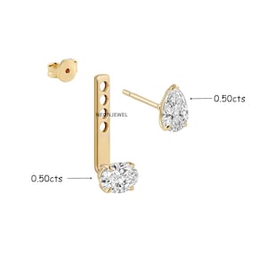 Puede incluir: Un conjunto de pendientes tipo ear jacket de oro con un diamante en forma de pera y una pieza vertical con un diamante ovalado. El texto NEONJEWEL es visible. Cada diamante está marcado como 0,50cts. Incluye un cierre de oro a juego.
