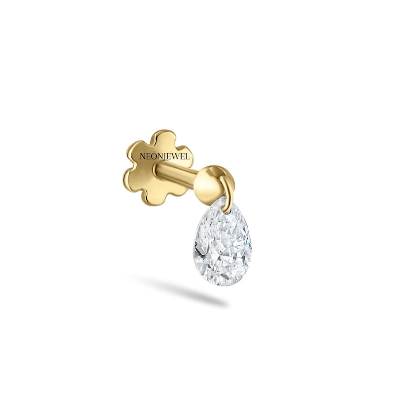 May include: A single gold earring with a pear-shaped diamond pendant. The earring has a flower-shaped backing with the text "NEONJEWEL". The diamond sparkles. The earring is set against a white background.