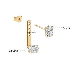 May include: A gold ear jacket earring set featuring two oval-cut clear stones, each labelled 0.50cts. The design includes a post earring with a single stone and a separate vertical bar attachment with four holes and a second stone at the base.