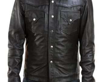 May include: Black leather shirt-jacket with a classic collar, two chest pockets, and silver-tone button closures. The jacket has a tailored fit and is worn over blue denim jeans. A stylish outerwear piece.