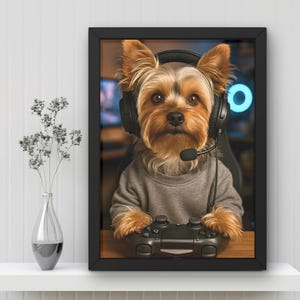 Pu&ograve; includere: Opera d'arte incorniciata con un Yorkshire Terrier che indossa una cuffia e tiene in mano un controller per videogiochi. Il cane indossa un maglione grigio. Lo sfondo mostra una configurazione di gioco con una luce al neon blu.