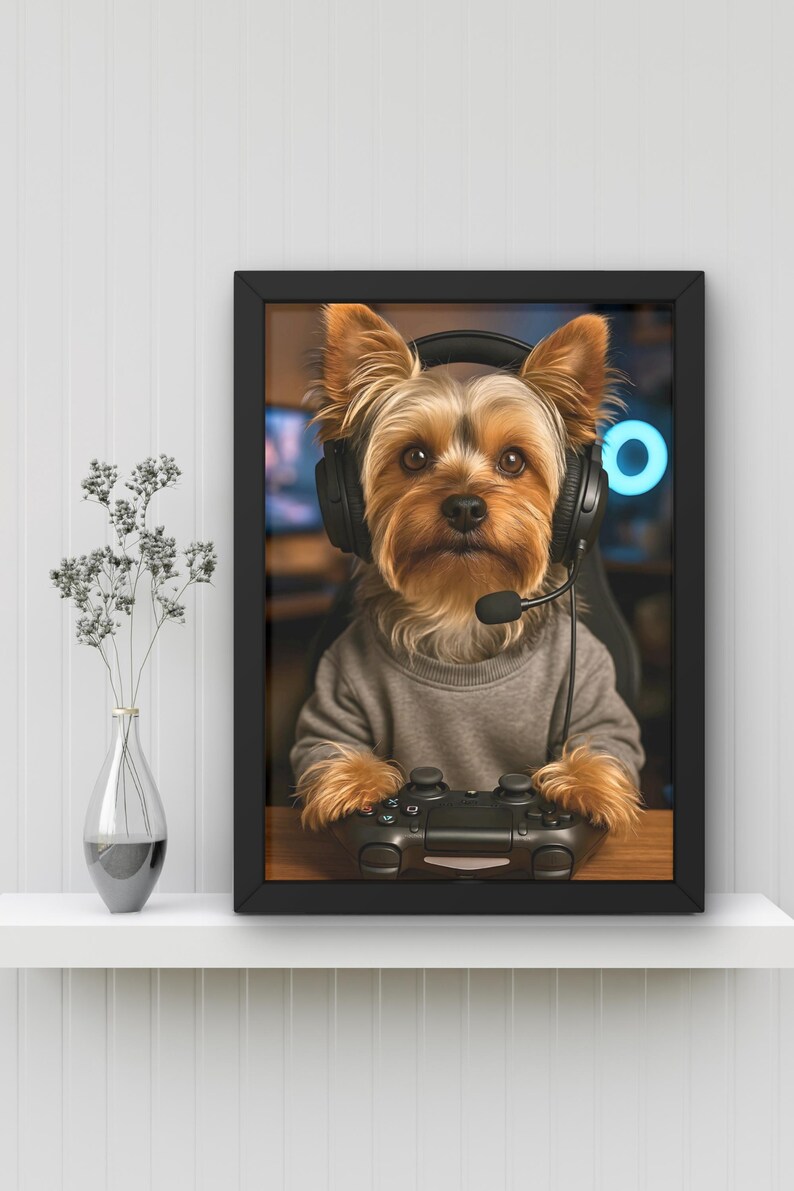 Pu&ograve; includere: Opera d'arte incorniciata con un Yorkshire Terrier che indossa una cuffia e tiene in mano un controller per videogiochi. Il cane indossa un maglione grigio. Lo sfondo mostra una configurazione di gioco con una luce al neon blu.