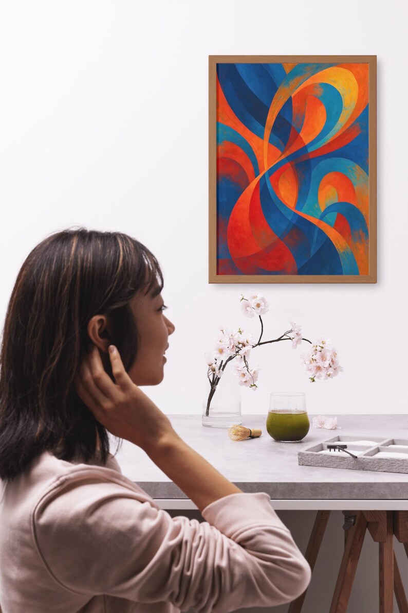 May include: An abstract painting in a wooden frame, featuring flowing shapes in shades of blue, orange, and red. A woman is seen in the foreground, with a table set with a glass of green liquid, a small brush, and a tray.