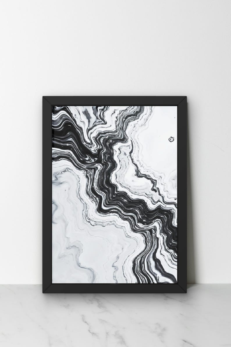 May include: Black and white abstract art print in a black frame. The artwork features a flowing, marbled design with swirling patterns. The contrast between the black and white creates a dynamic visual effect, suitable for modern home decor.