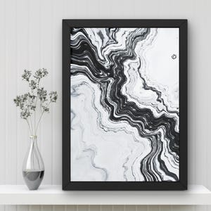 May include: Black and white abstract art print in a black frame. The artwork features a flowing, marbled design. A clear glass vase with dried flowers sits on a white shelf below the framed art.