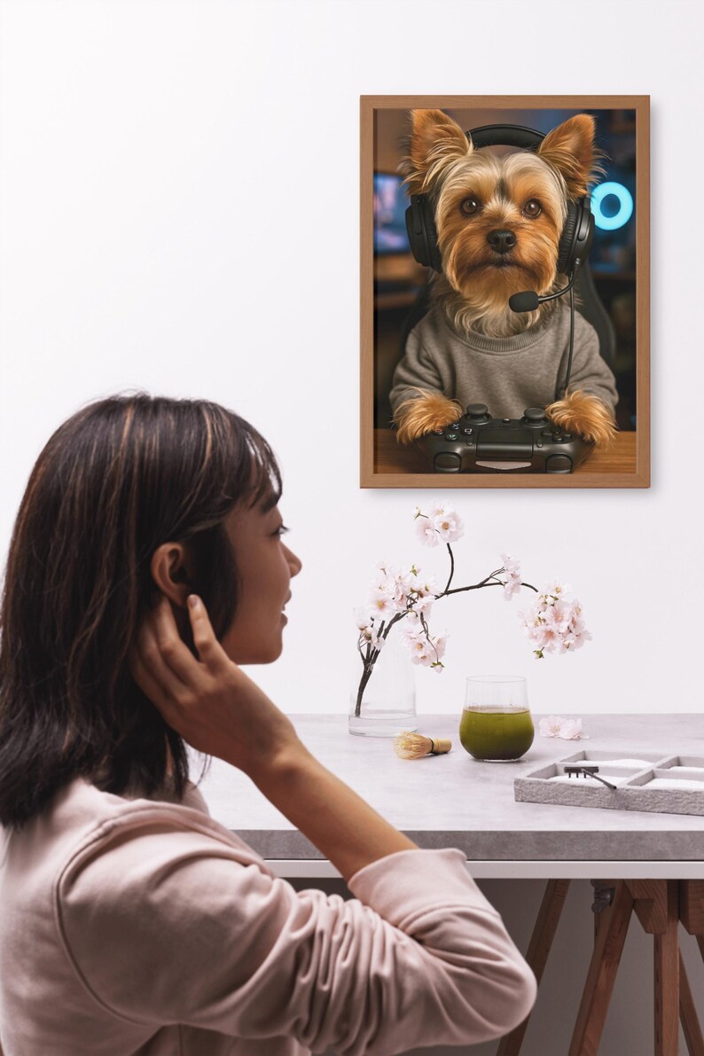 Pu&ograve; includere: Stampa incorniciata con un Yorkshire Terrier con cuffie e un controller di gioco. Il cane indossa un maglione grigio. L'immagine &egrave; ambientata su uno sfondo sfocato con un anello al neon blu.