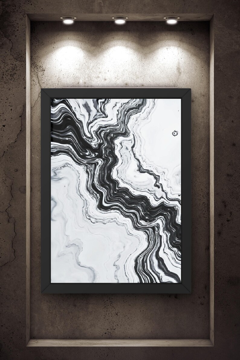 May include: A framed abstract art print with a black and white marble design. The artwork features flowing, swirling patterns in shades of gray and black against a white background. The print is displayed in a black frame, mounted on a textured, dark brown wall.