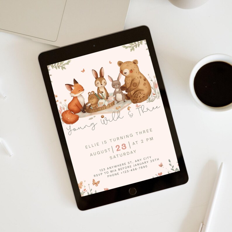 May include: A digital invitation on a tablet for a third birthday party. The design features watercolor illustrations of woodland animals, including a fox, bear, and rabbits. The text reads "Young Wild & Three" and includes party details.