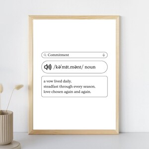 May include: A framed print with the definition of "Commitment." The definition includes the word, pronunciation, and a short description. The frame is a light wood color, and the background is white.