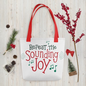 May include: White canvas tote bag with red handles. The bag has a green and red design with the text "Repeat the Sounding Joy" and musical notes.