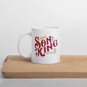 May include: White ceramic mug with a red and gold design that says "I am a Son of a King" with a shield graphic.