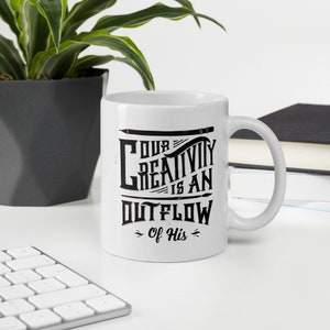 May include: White ceramic mug with a black graphic that reads "Our Creativity is an Outflow of His".